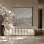 White tufted sofa in a room with a large abstract painting on the wall.