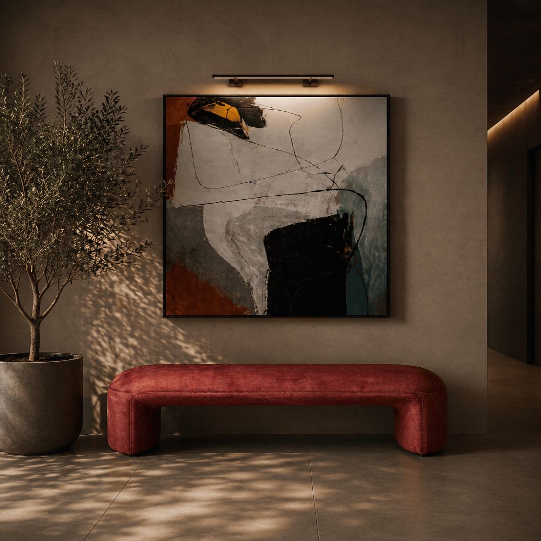 Abstract painting on a wall above a red bench with a plant to the side.
