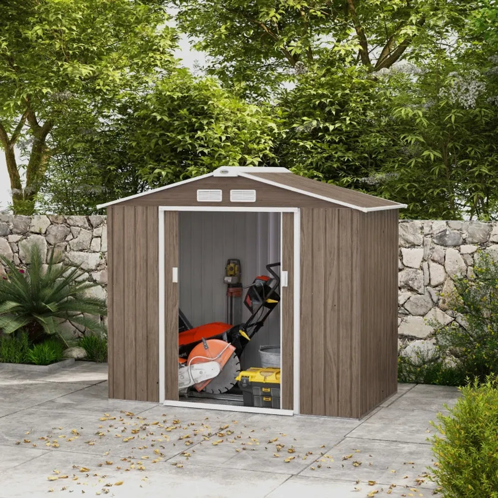 Wooden shed with tools inside, surrounded by greenery and a stone wall.