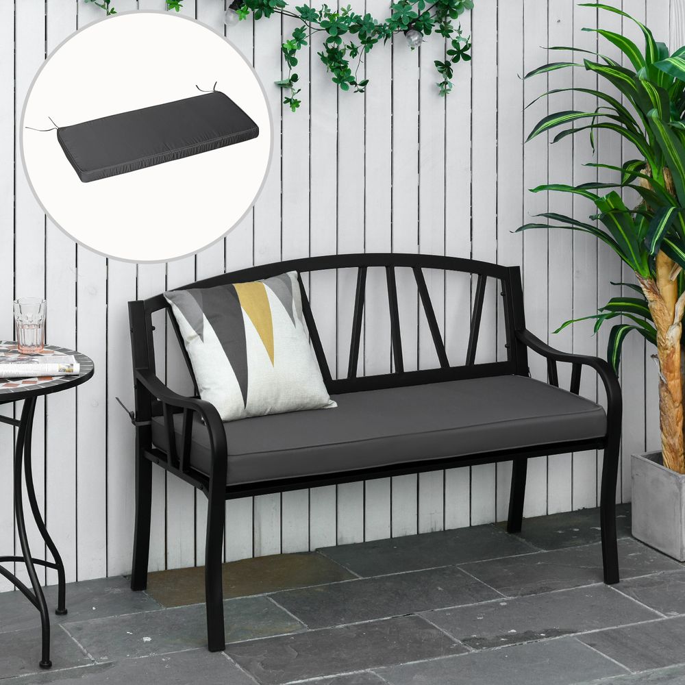 Black metal bench with gray cushion and decorative pillows against a white wooden wall.
