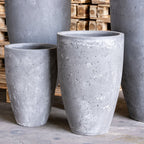 Set of gray concrete planters on a wooden surface with stacked wooden planks in the background.