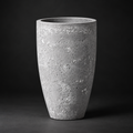 A tall, textured concrete planter pot with a tapered shape, shown on a dark studio background.