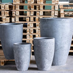 Set of four gray concrete planters in front of wooden pallets