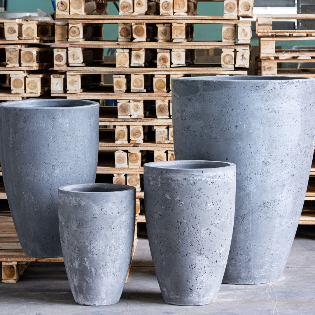 Set of four gray concrete planters in front of wooden pallets