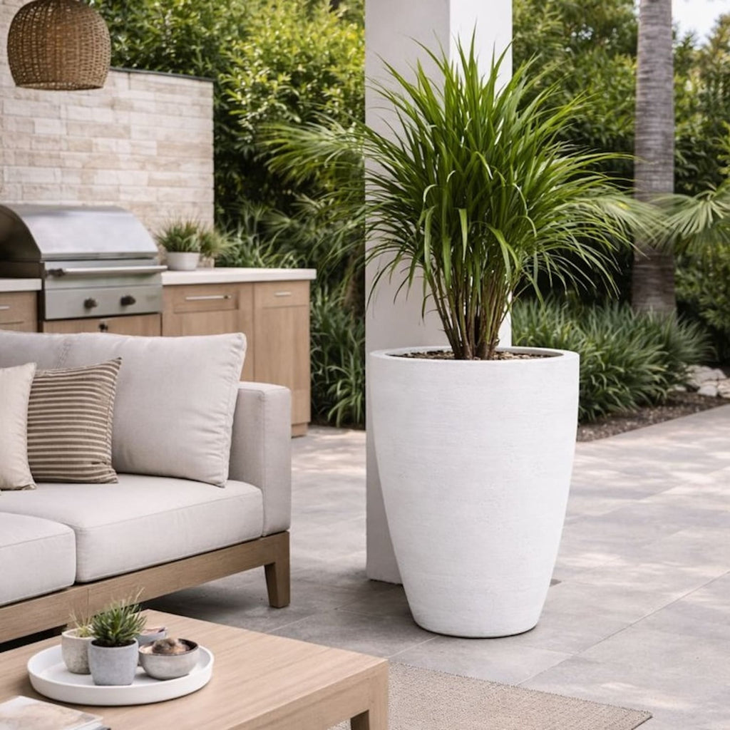 Outdoor patio with a sofa, coffee table, and large planter in a garden setting.