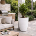 Outdoor patio with a sofa, coffee table, and large planter in a garden setting.