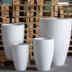 Set of white concrete planters in front of wooden pallets