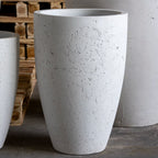 White concrete planters on a gray floor with wooden pallets in the background