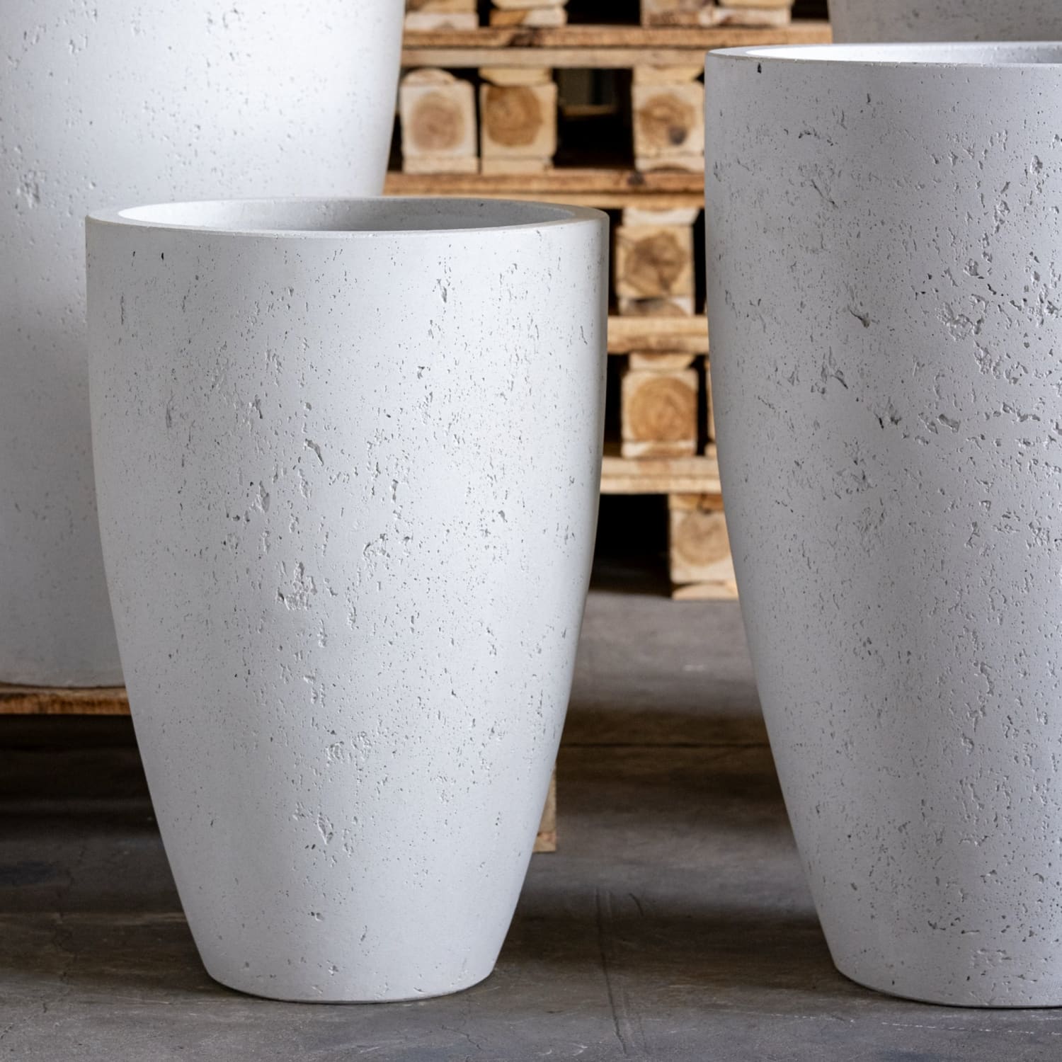 Two large white planters with a wooden pallet in the background