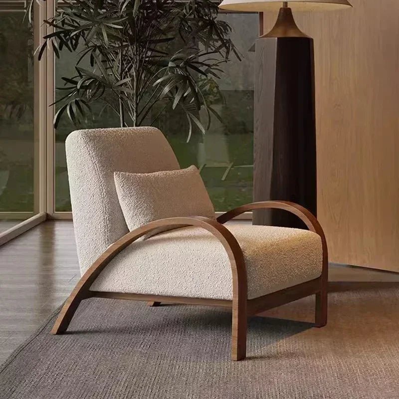 Beige armchair with wooden frame in a room with a plant and lamp.