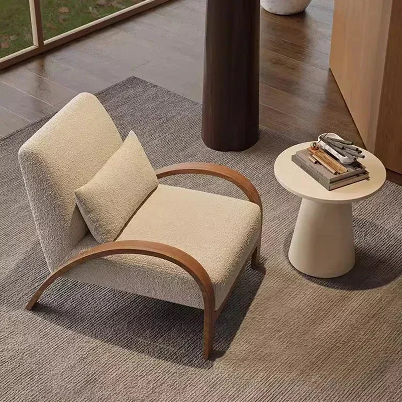 Beige armchair with wooden armrests in a room with a rug and small table.