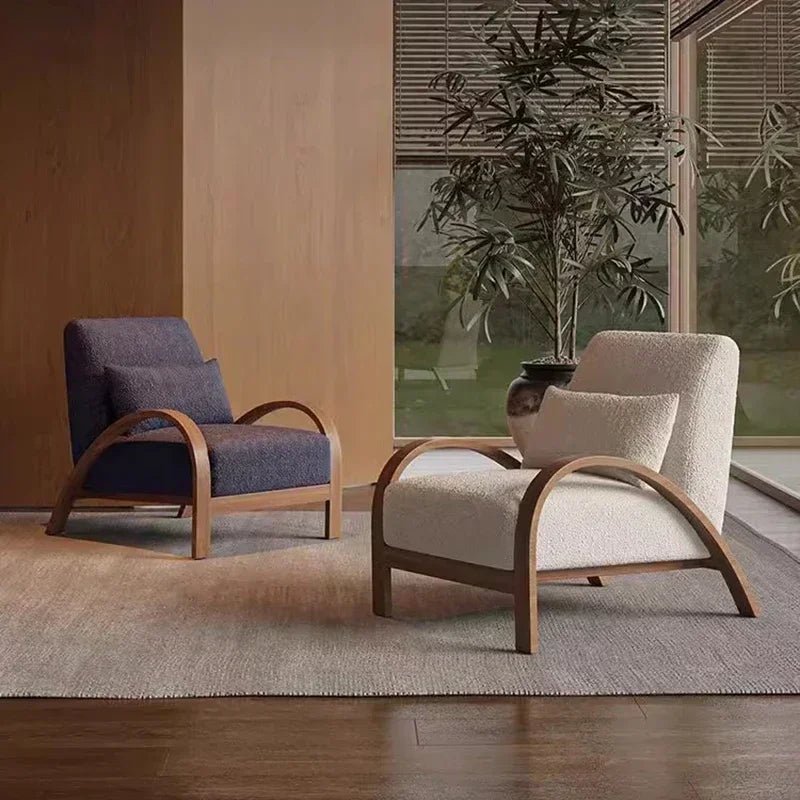 Two modern style armchairs, one with deep blue and brown lines, the other with beige and light brown lines, both with high-quality fabric seats, positioned in a room with a large window and a plant in the background.