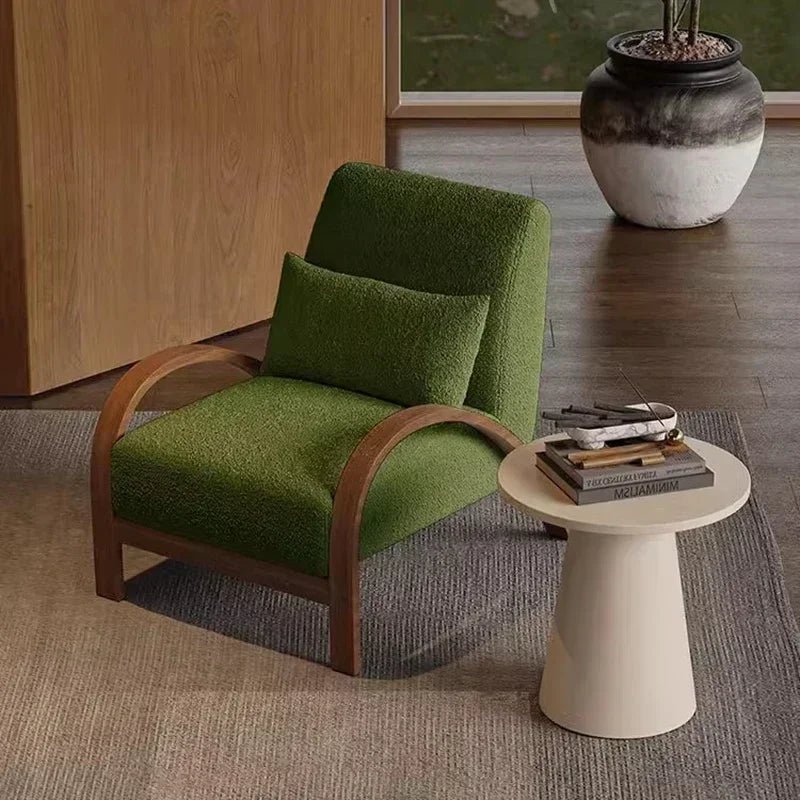 Green armchair with wooden armrests in a room with a small table and decorative items.