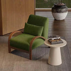 Green armchair with wooden armrests in a room with a small table and decorative items.